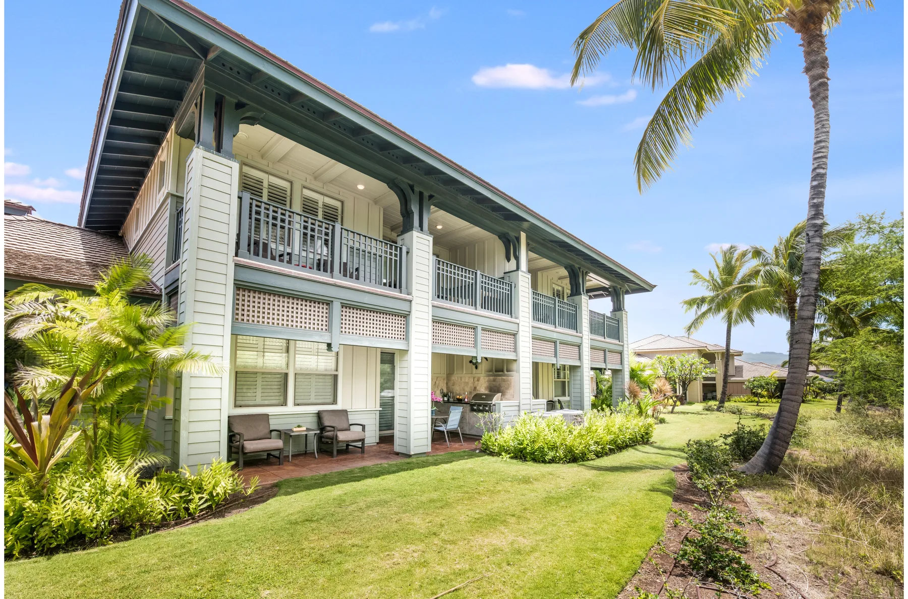 A two-story building with covered balconies overlooks a landscaped lawn.