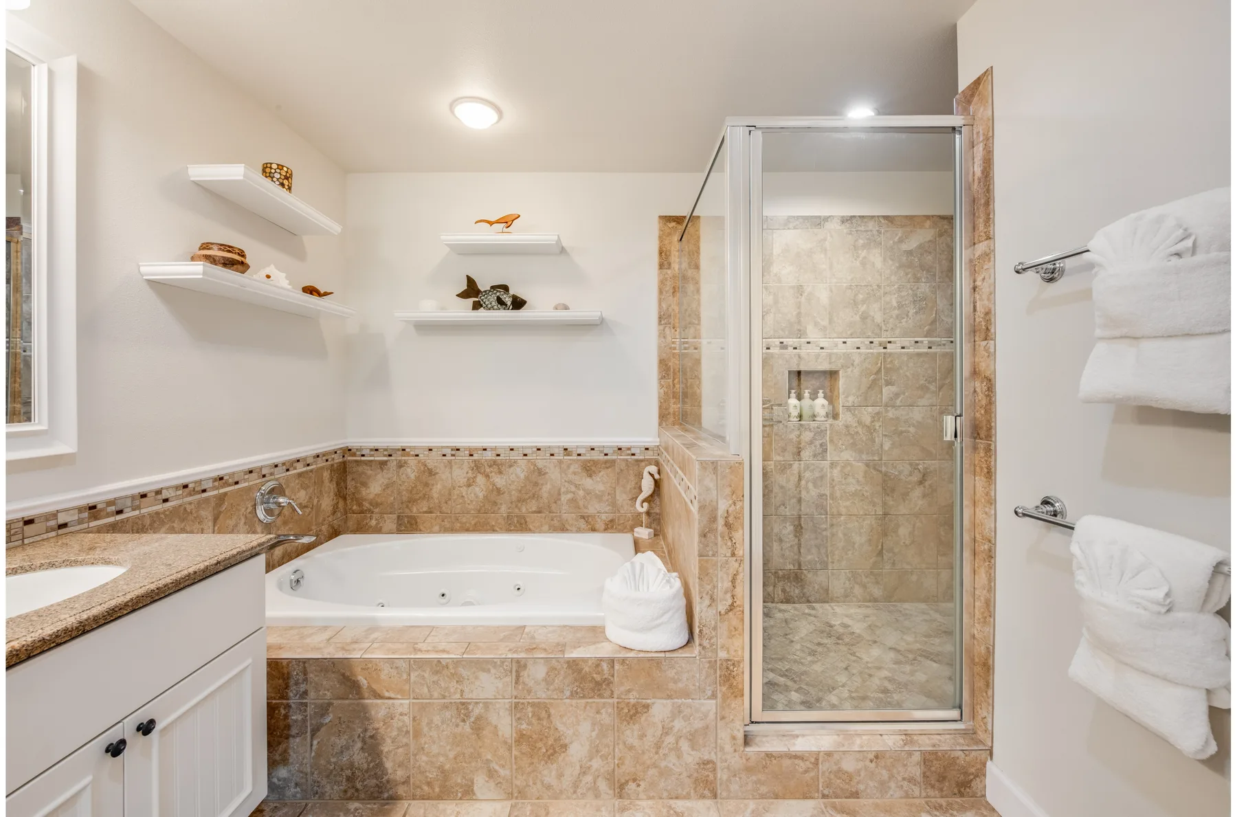 A bathroom with a bathtub, tiled walls, and a glass shower enclosure.