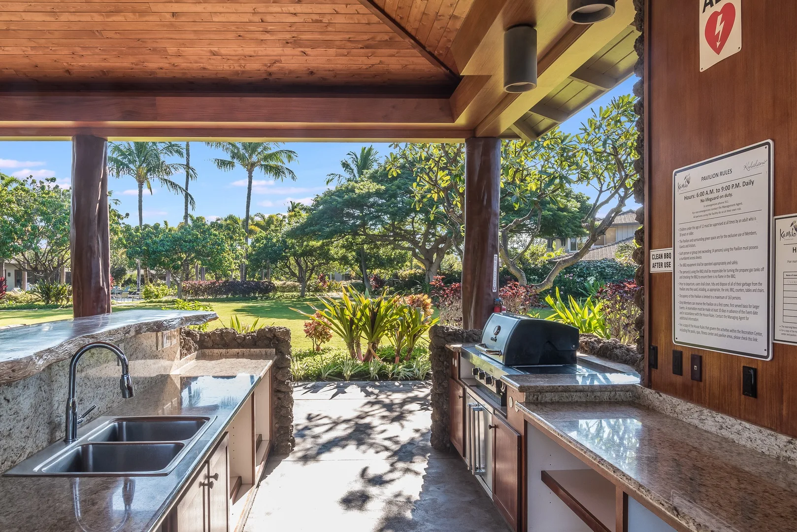 An outdoor kitchen with counters and a grill overlooks a landscaped garden.