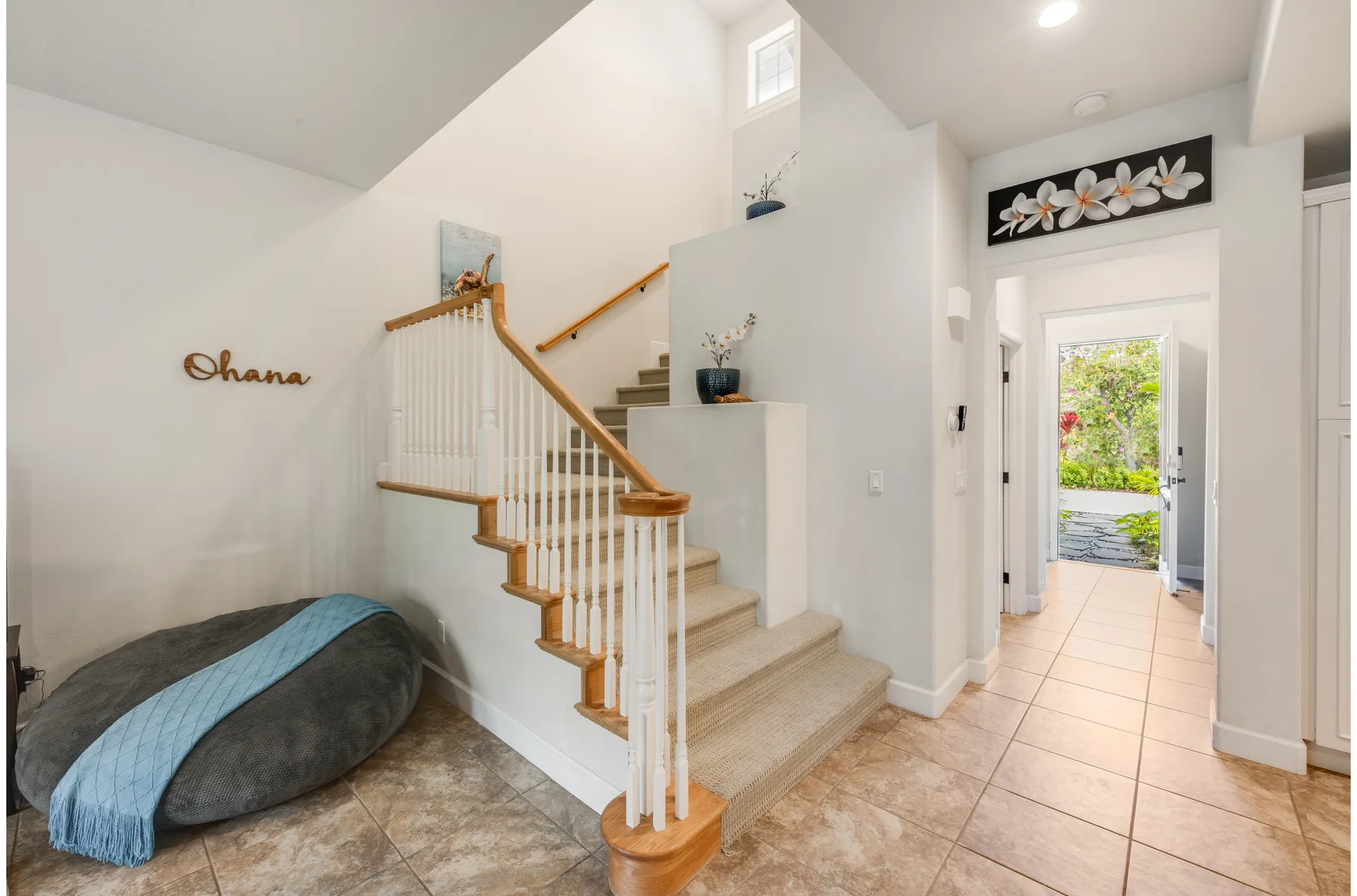 A bright entryway with a staircase and an open doorway to the outside.