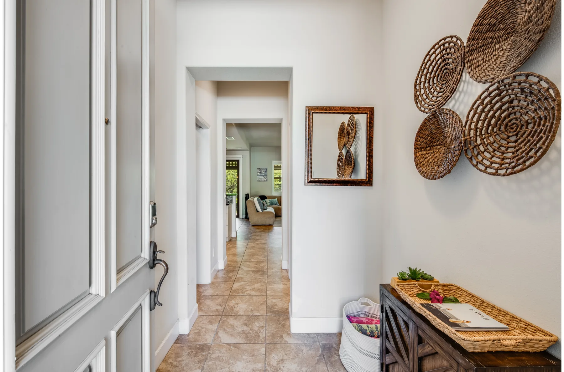 A bright hallway with tiled flooring and woven wall decorations.
