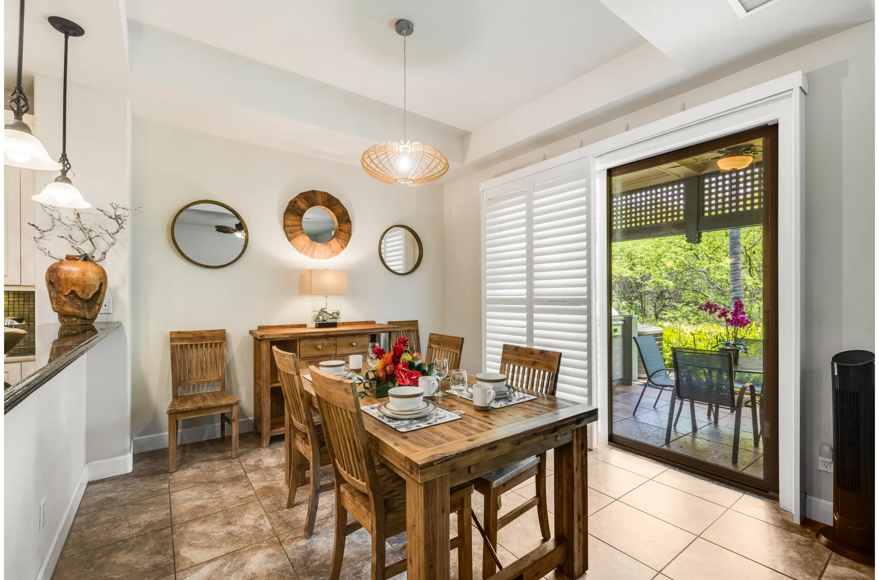 A dining area with a wooden table set beside an open patio doorway.