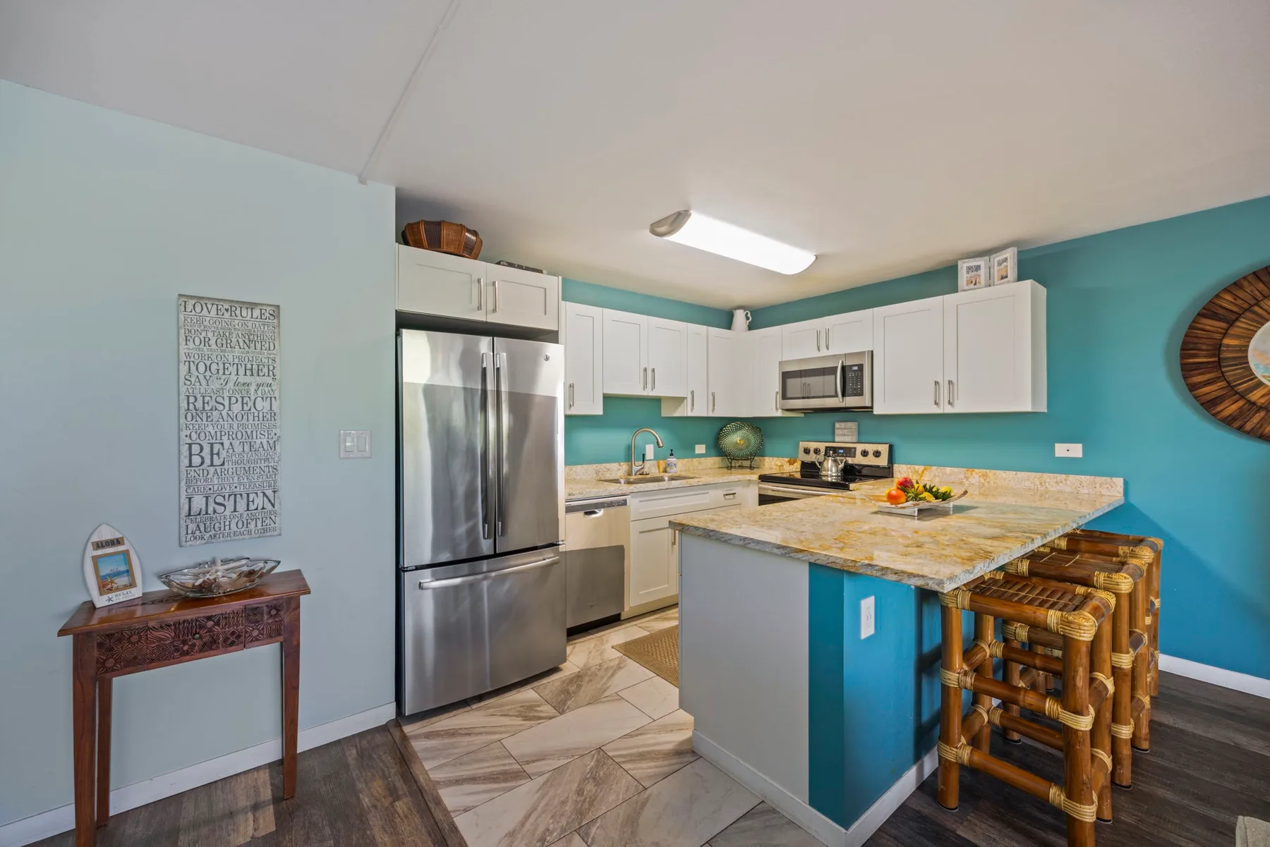Una cocina luminosa con gabinetes blancos, electrodomésticos de acero inoxidable y una isla central.