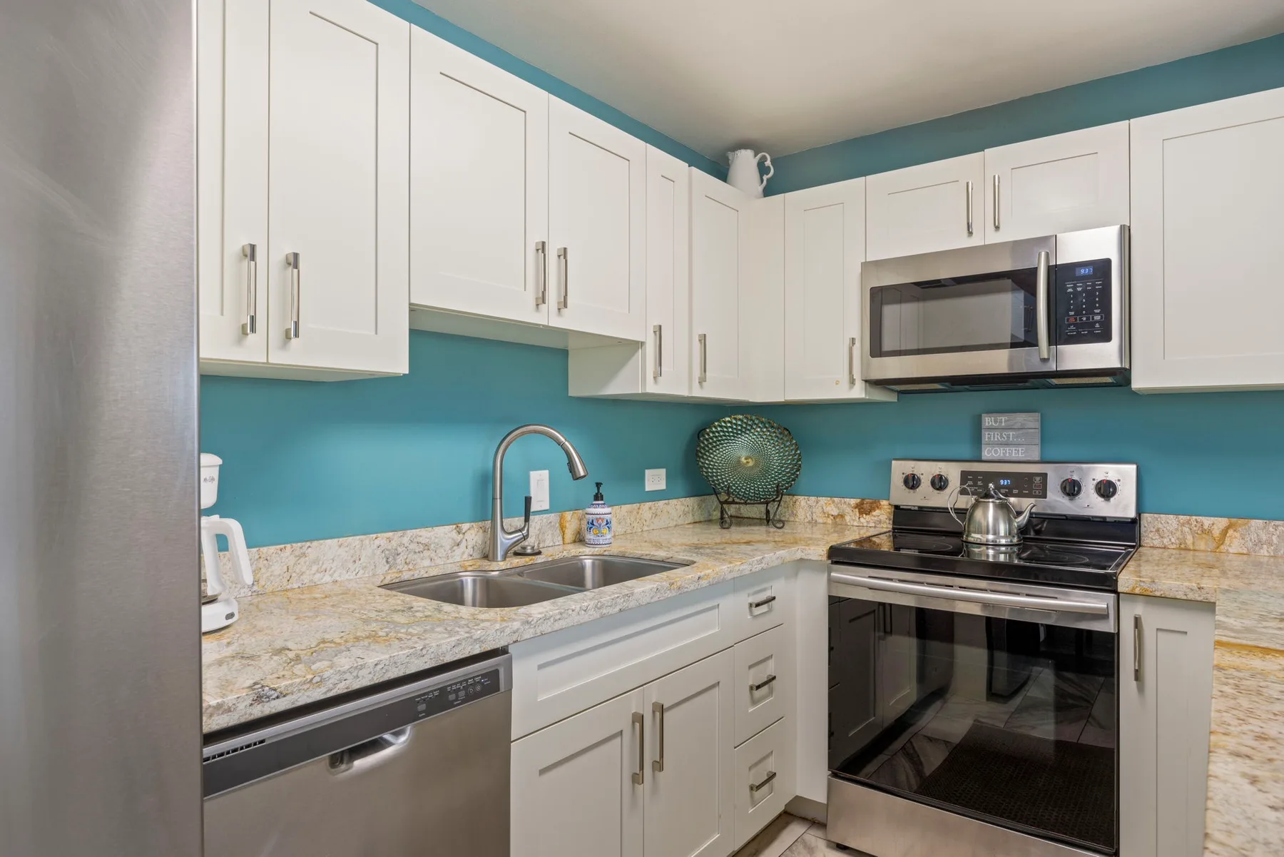 Una cocina luminosa con gabinetes blancos, un fregadero y electrodomésticos de acero inoxidable.