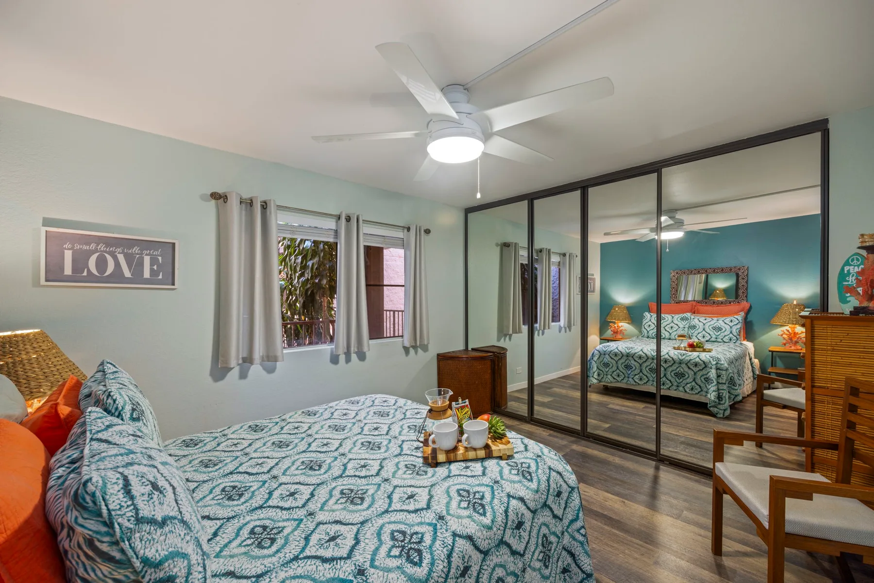 Un dormitorio con ropa de cama estampada, puertas de armario con espejo y ventilador de techo.