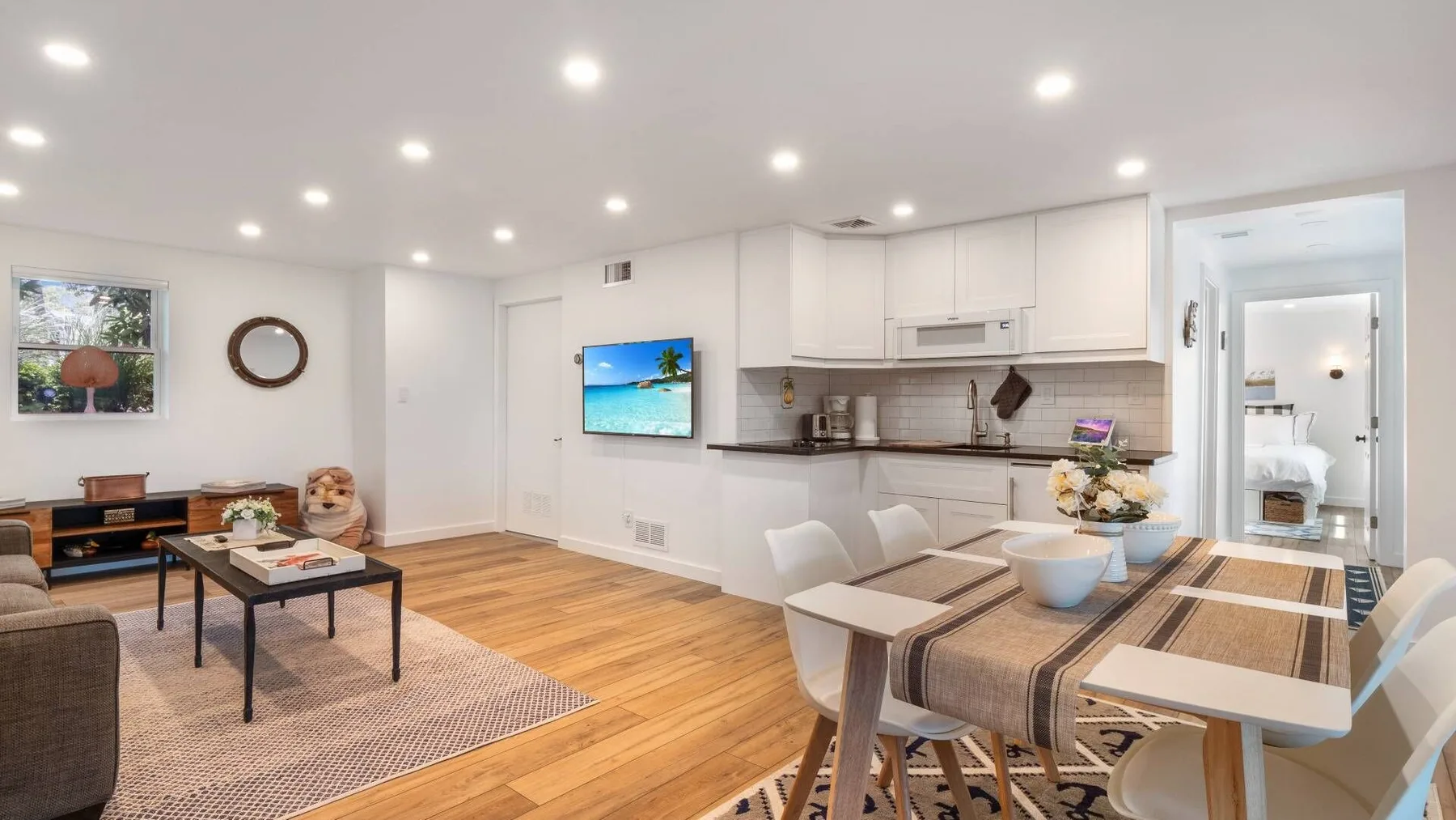 A bright open-plan living, dining, and kitchen area with light wood flooring.