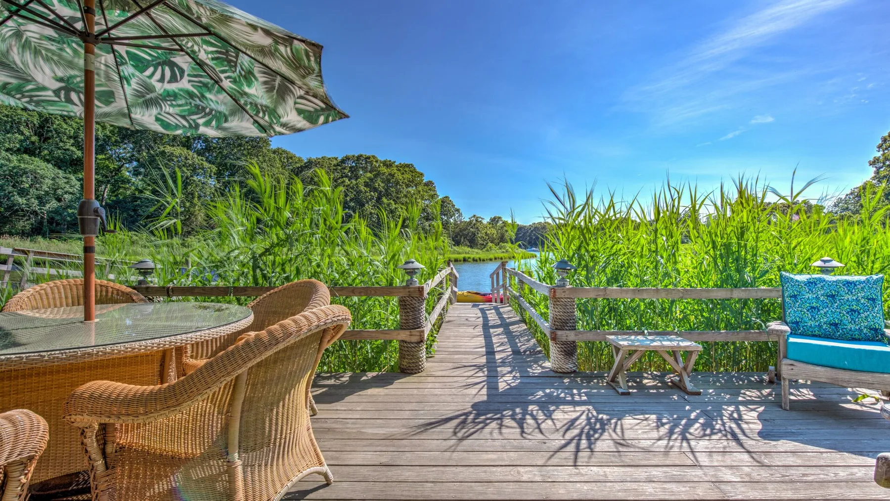 A wooden deck seating area overlooks a lush waterside landscape.