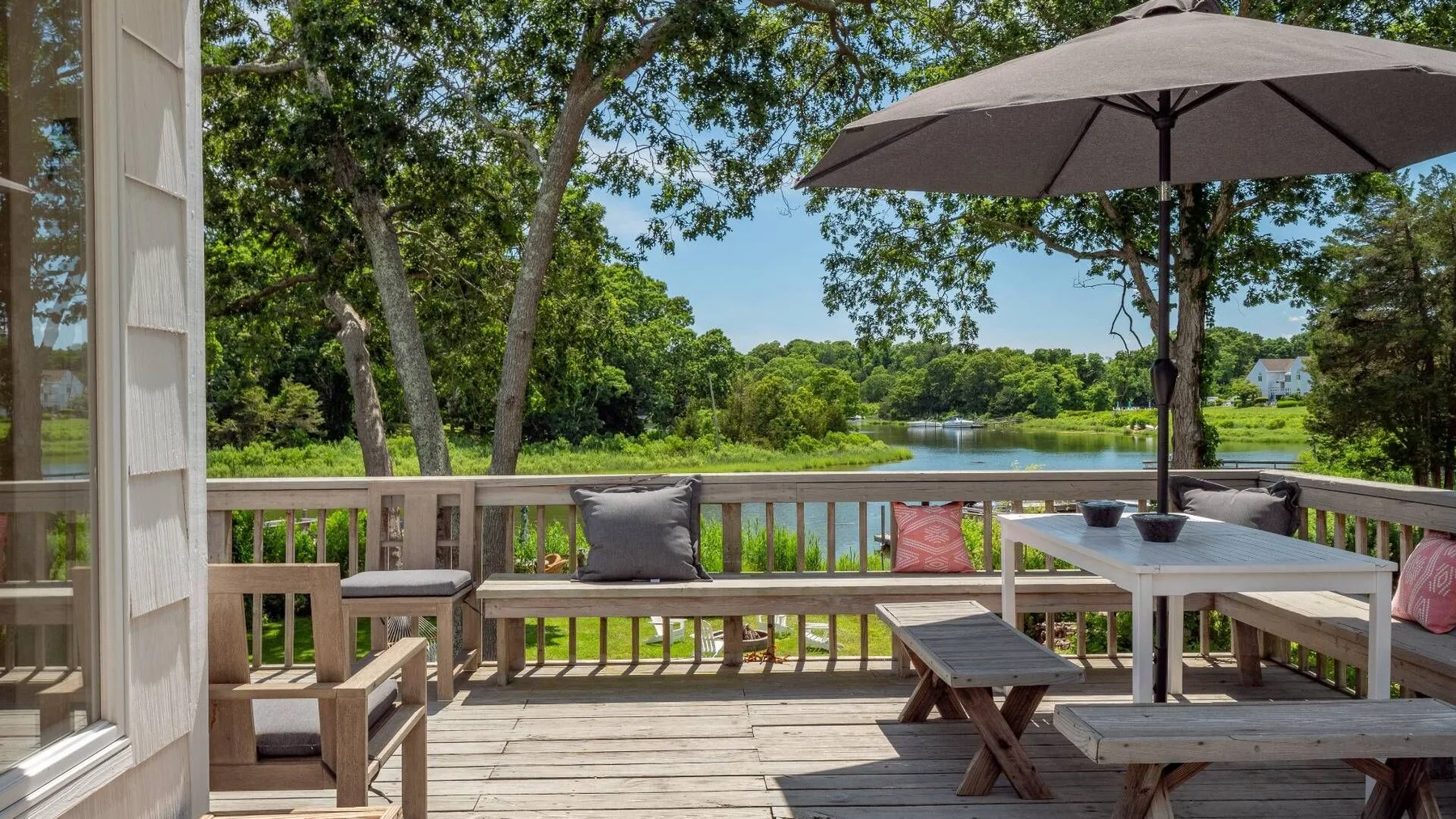 A wooden deck with outdoor seating overlooks a green landscape.