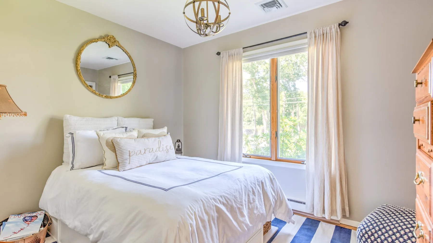 A bright bedroom with a neatly made bed beside a large window.