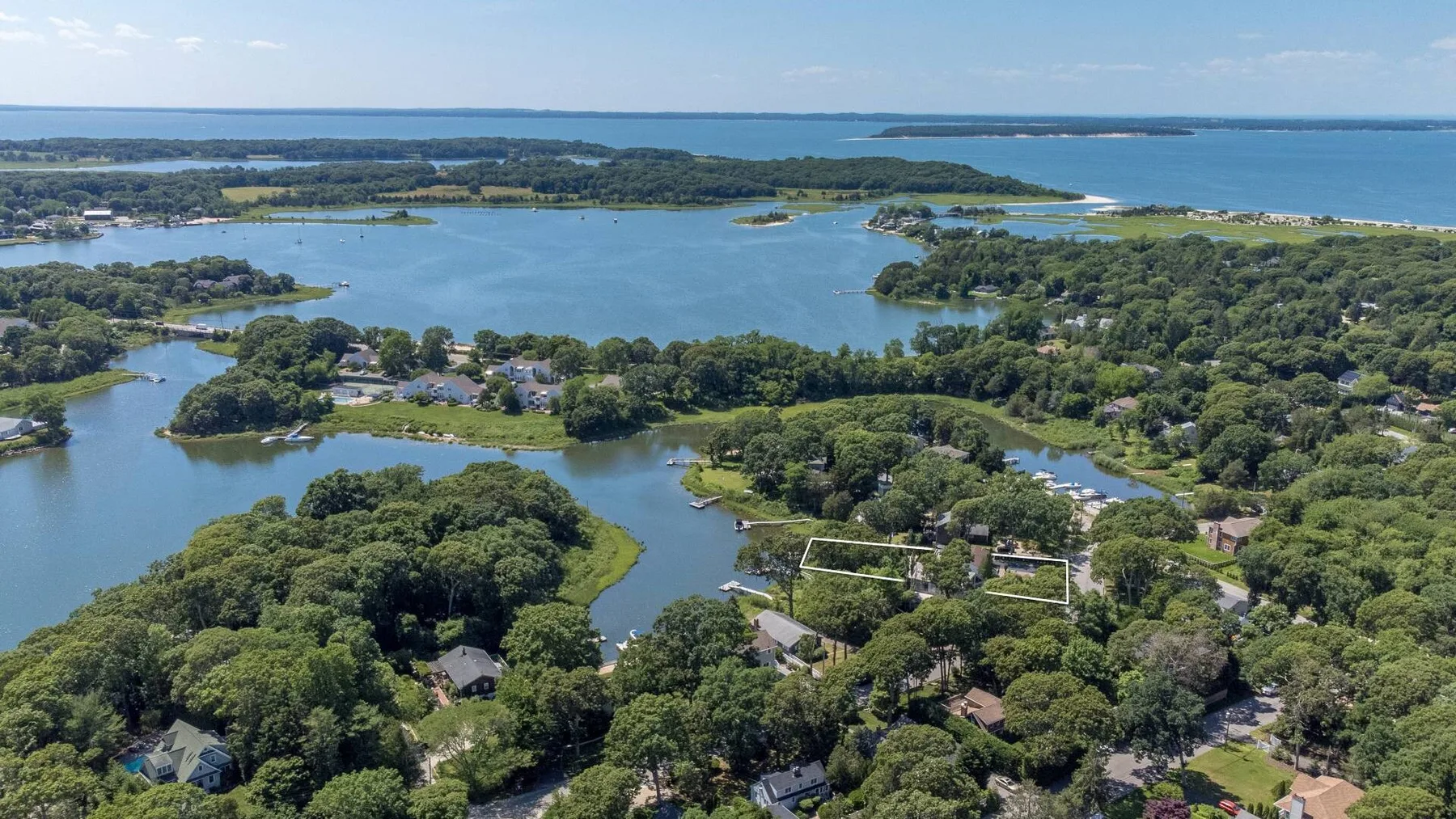 Aerial view of a wooded coastal area with waterways and scattered homes.