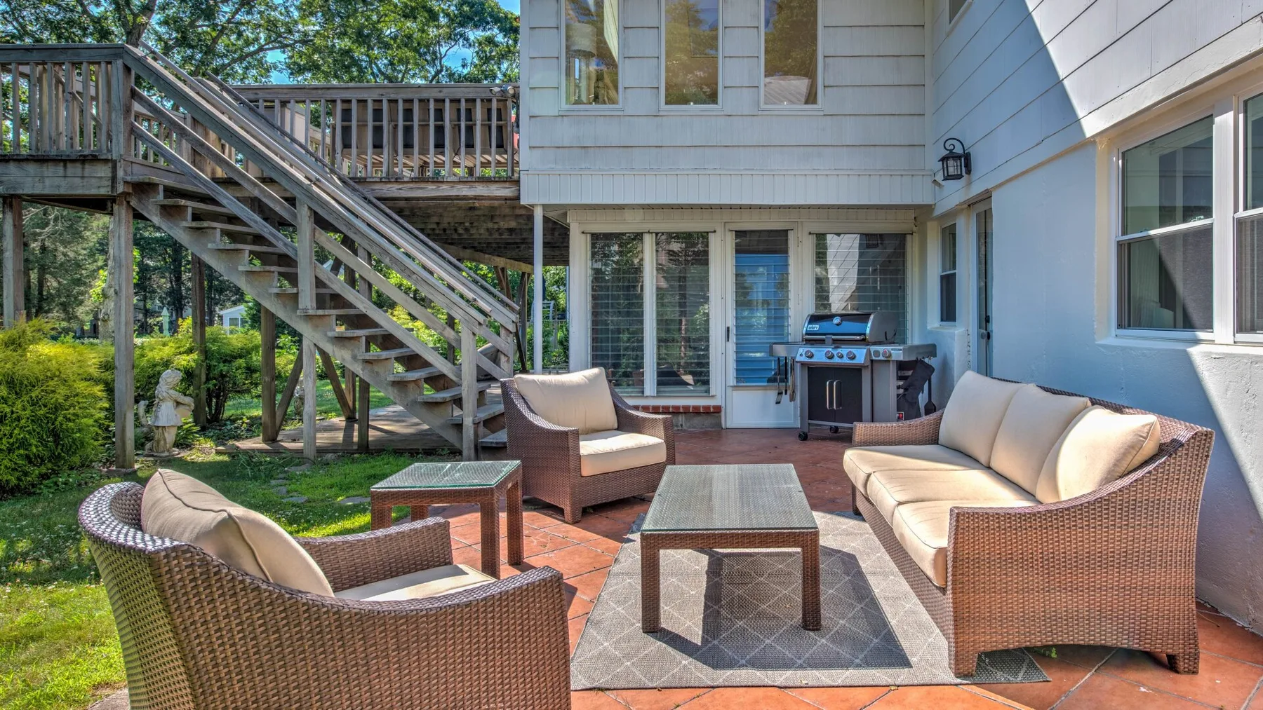 An outdoor patio with wicker seating and a dining table beside a house.