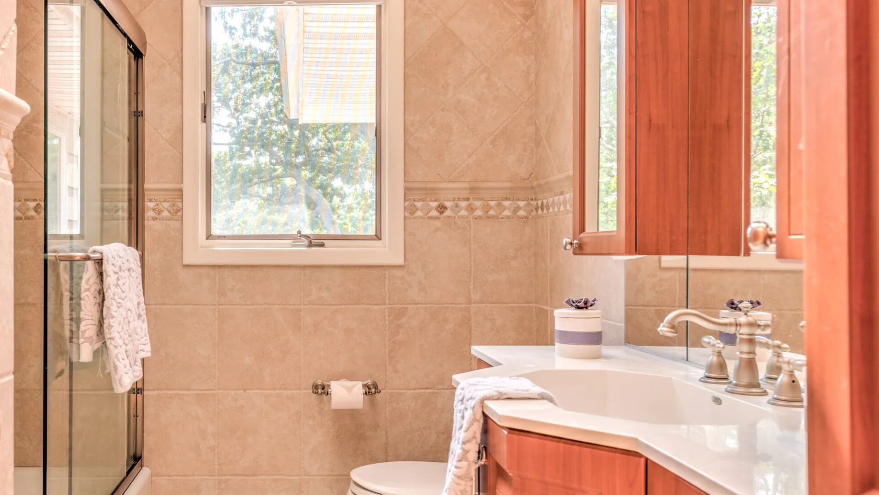 A bathroom with a glass shower, a sink, and a window.