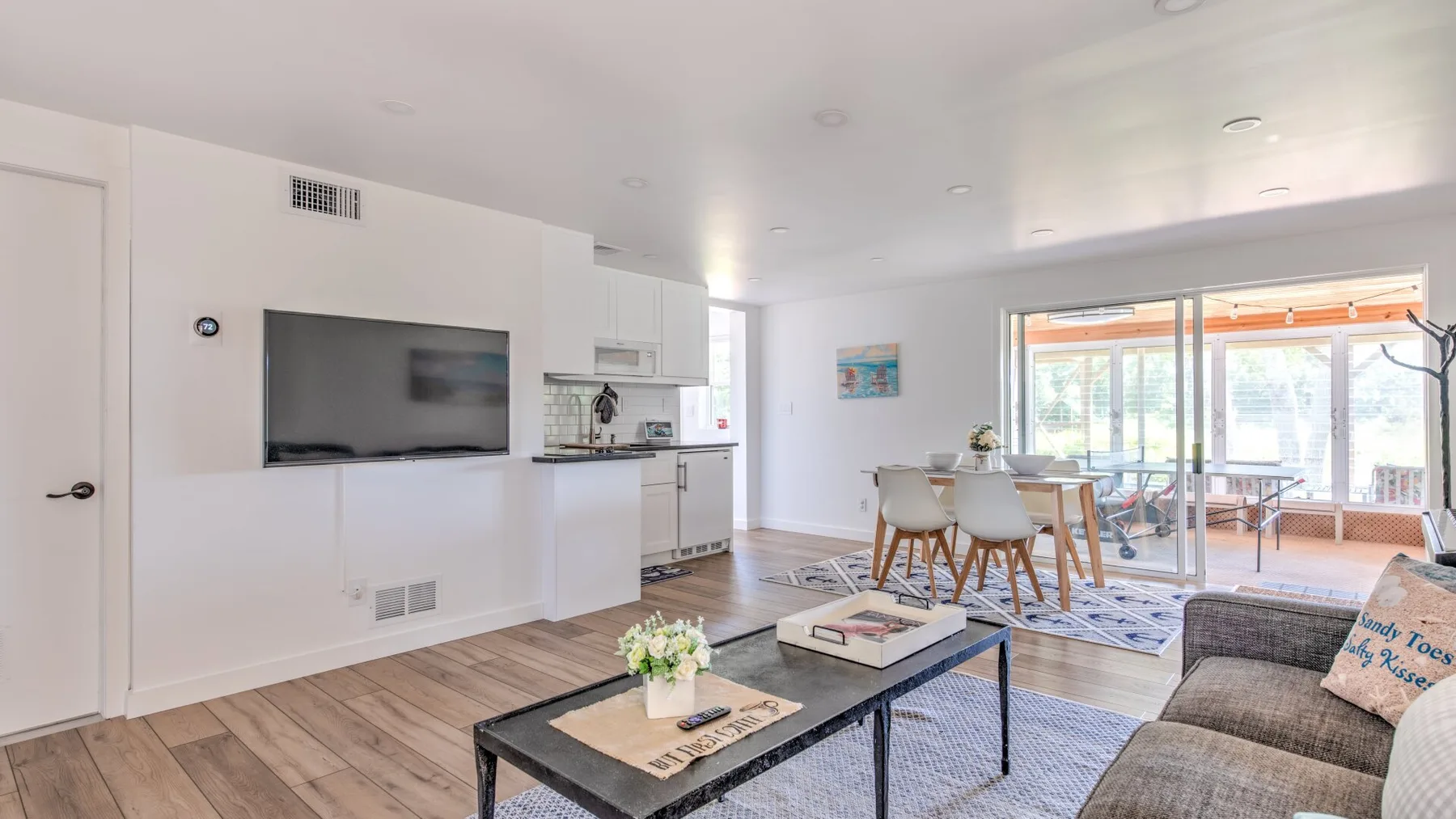 A bright open-plan living and dining area with a television and sliding glass doors.