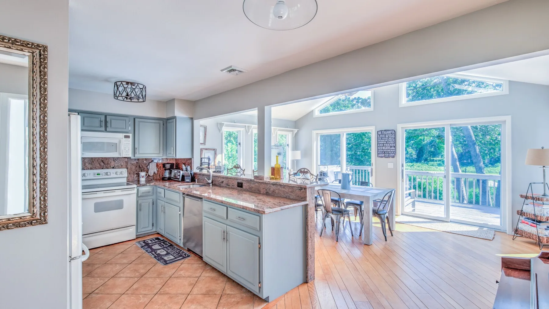 An open kitchen and dining area with large windows overlooking greenery.