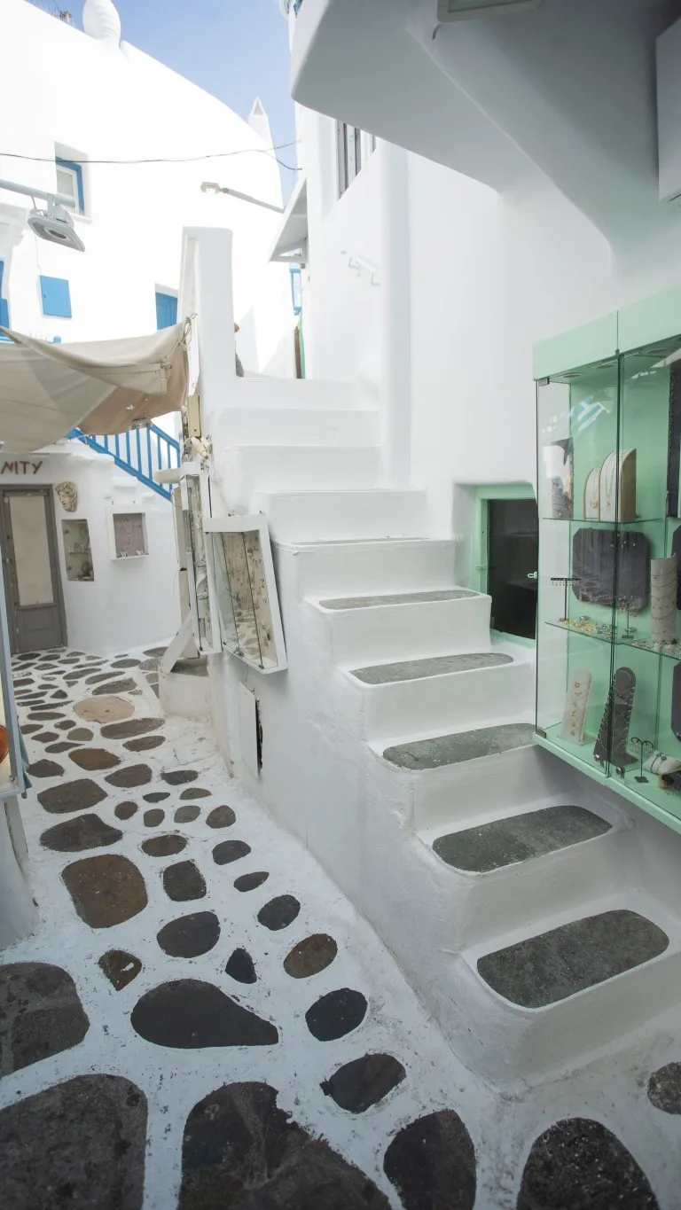 A white outdoor stairway with dark stone insets beside a glass display cabinet.