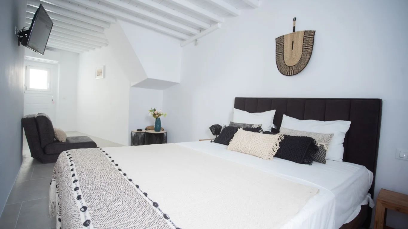 A bright bedroom with a bed and a dark upholstered headboard.