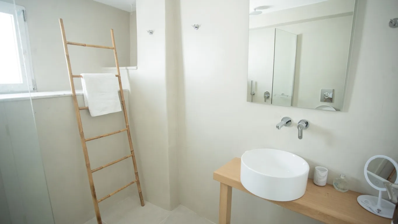 A bright bathroom with a sink, mirror, and towel ladder.
