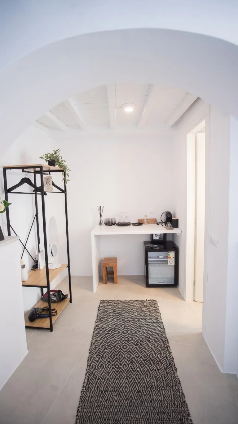 A bright room with a long woven rug and a small counter at the back.