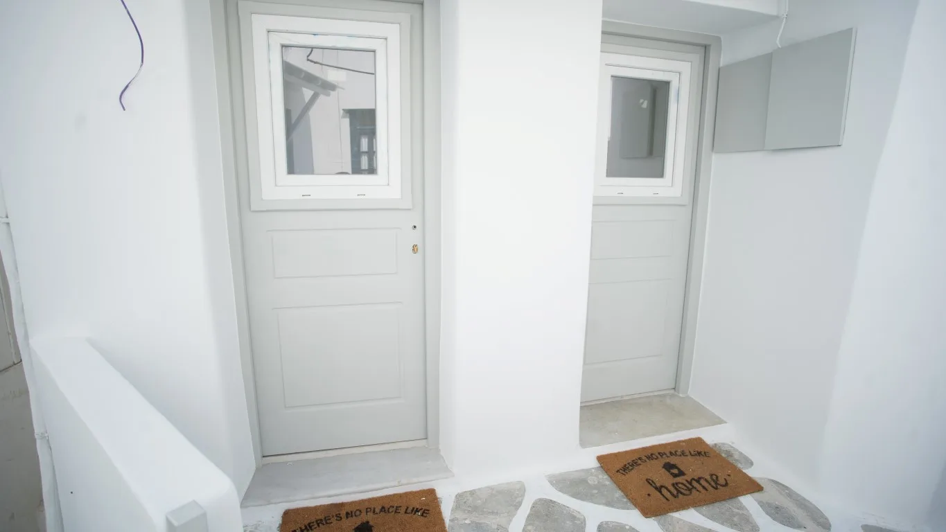 A bright white entryway with two doors and welcome mats on the floor.