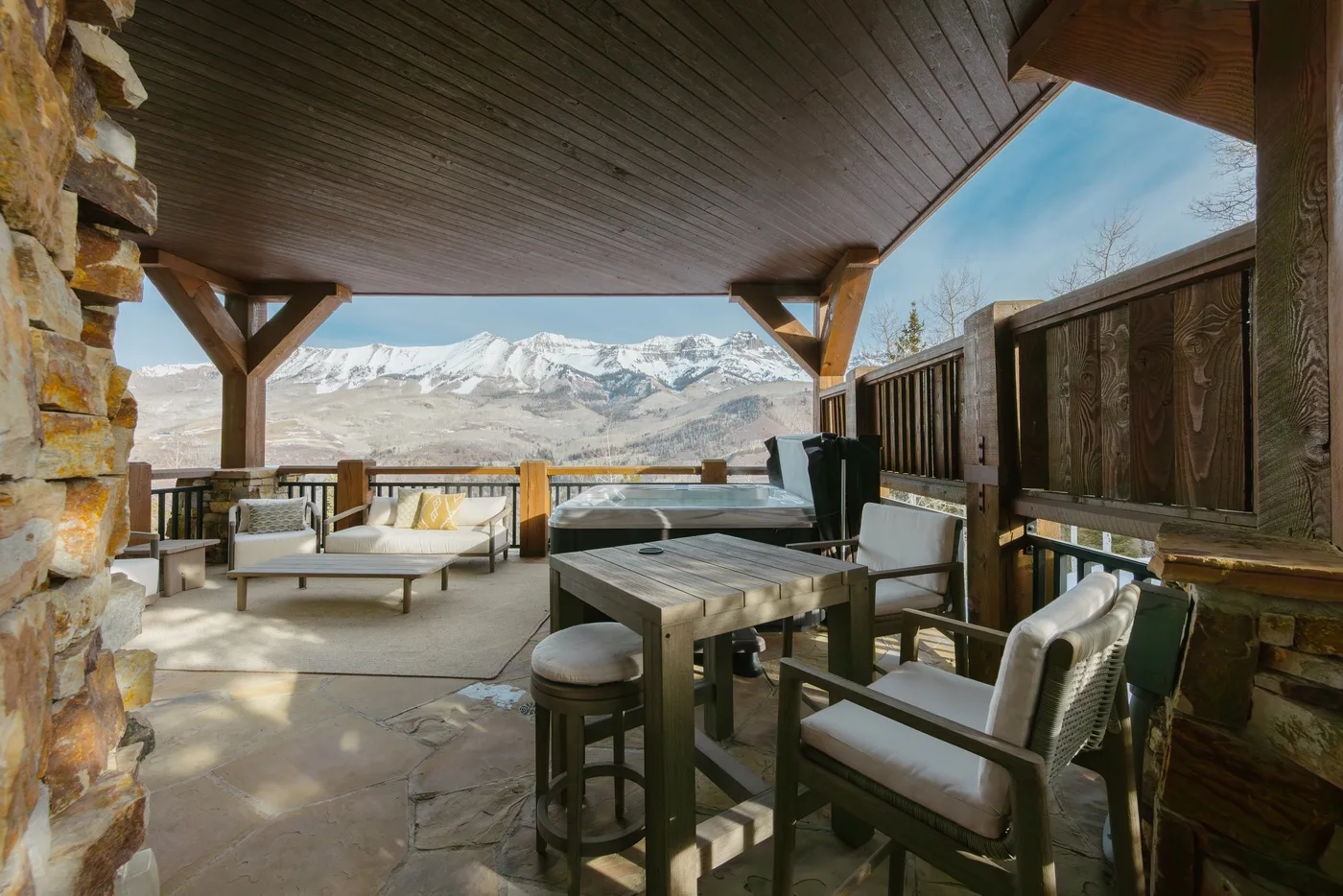 Un patio exterior cubierto con asientos y vistas a montañas nevadas.