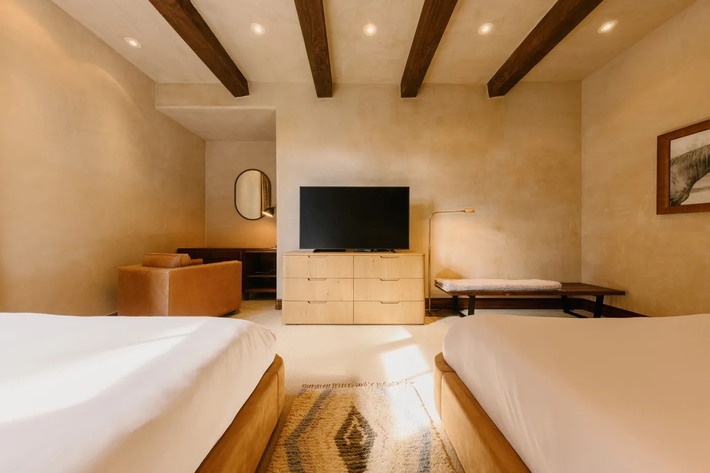 Un dormitorio con dos camas, un televisor y vigas expuestas en el techo.