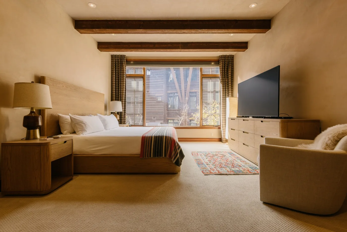 Un dormitorio con una cama, un televisor y una ventana grande.