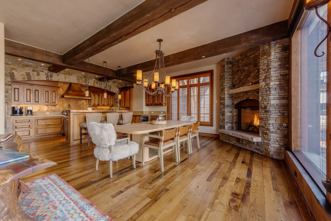 Una cocina rústica y zona de comedor con una mesa larga de madera y una chimenea de piedra.