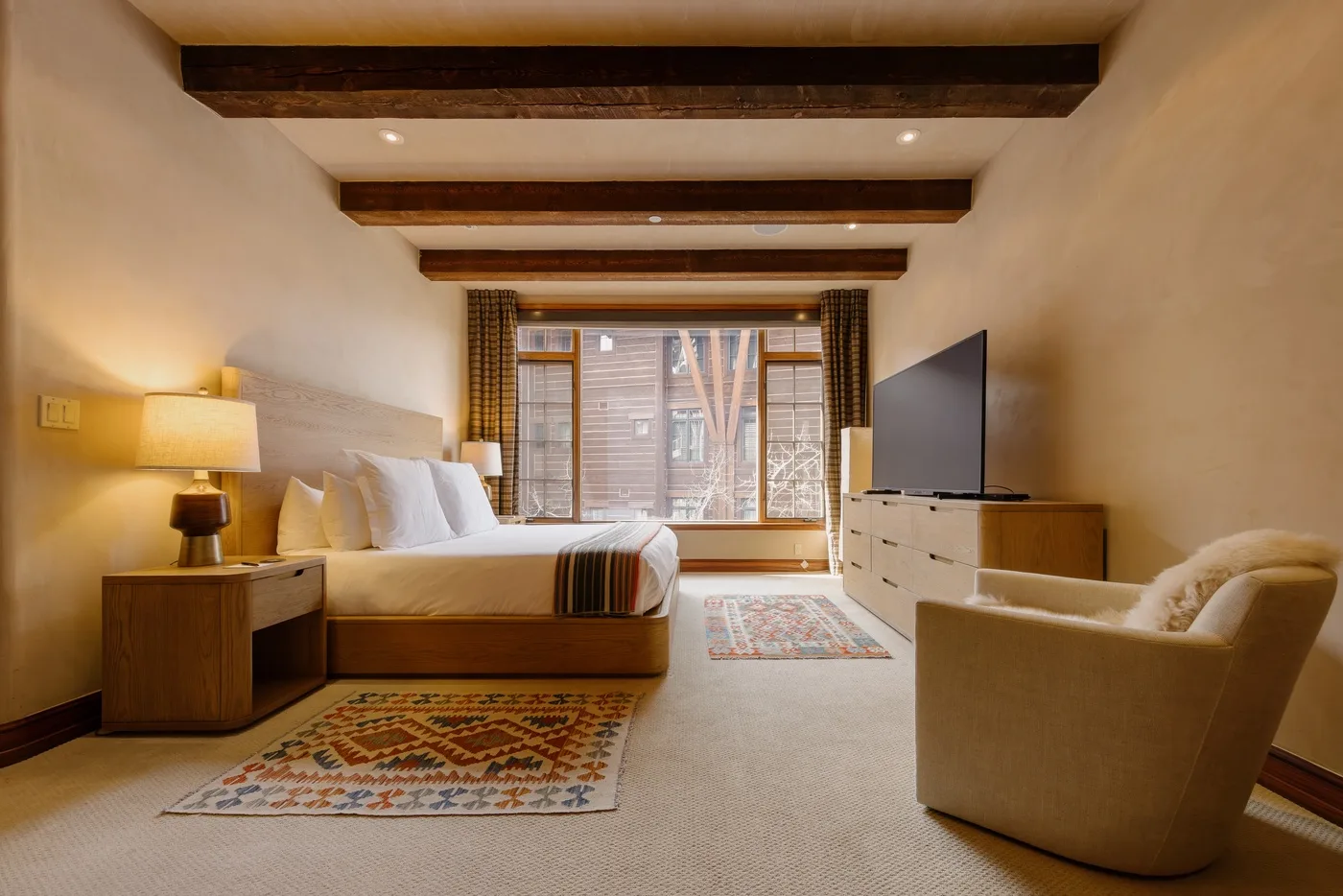 Un dormitorio con una cama, un televisor y una zona de estar junto a la ventana.