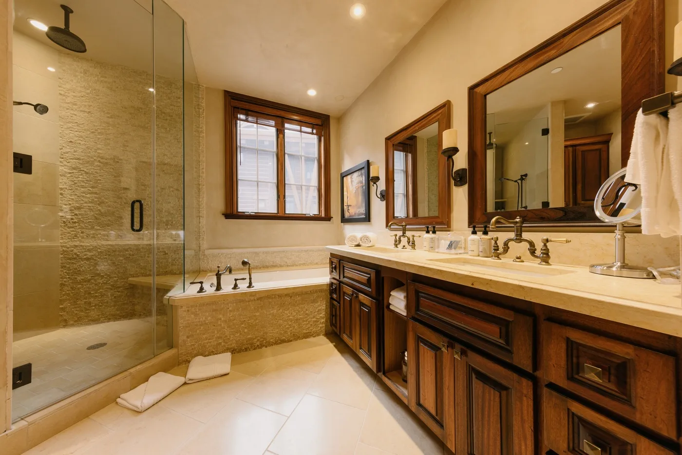 Un baño amplio con ducha de vidrio, bañera y un tocador largo.