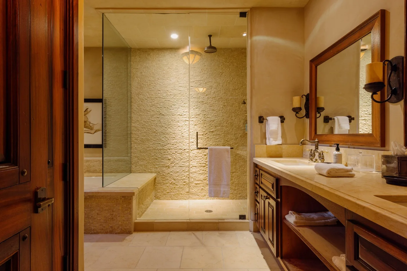 Un baño con ducha de vidrio y un tocador largo.