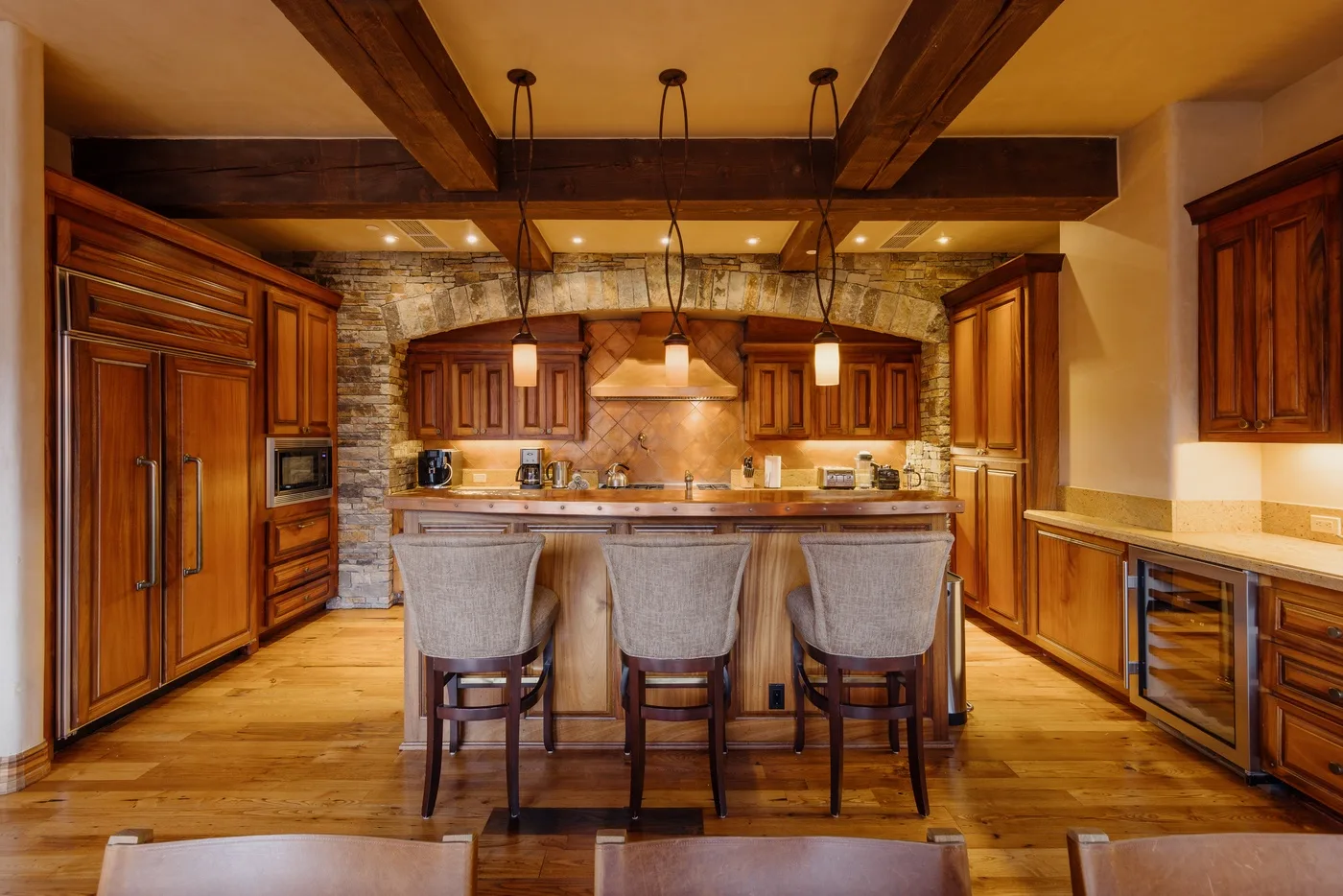 Una cocina amplia con una isla central, gabinetes de madera y paredes de piedra.