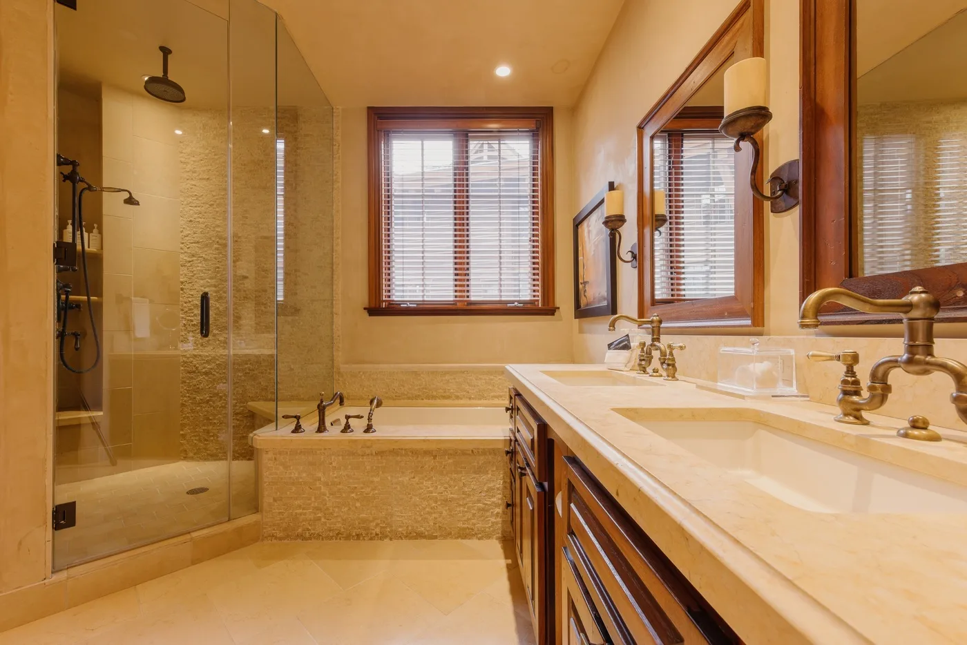 Un baño con ducha de vidrio, bañera y un largo tocador bajo las ventanas.