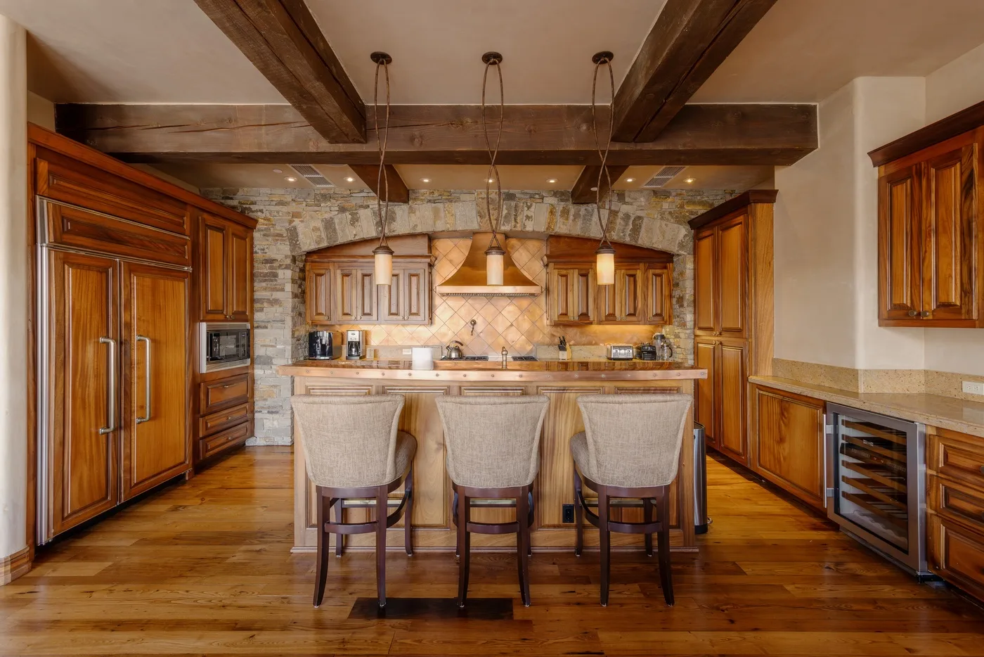 Una cocina amplia con gabinetes de madera, un revestimiento de piedra y una isla central.