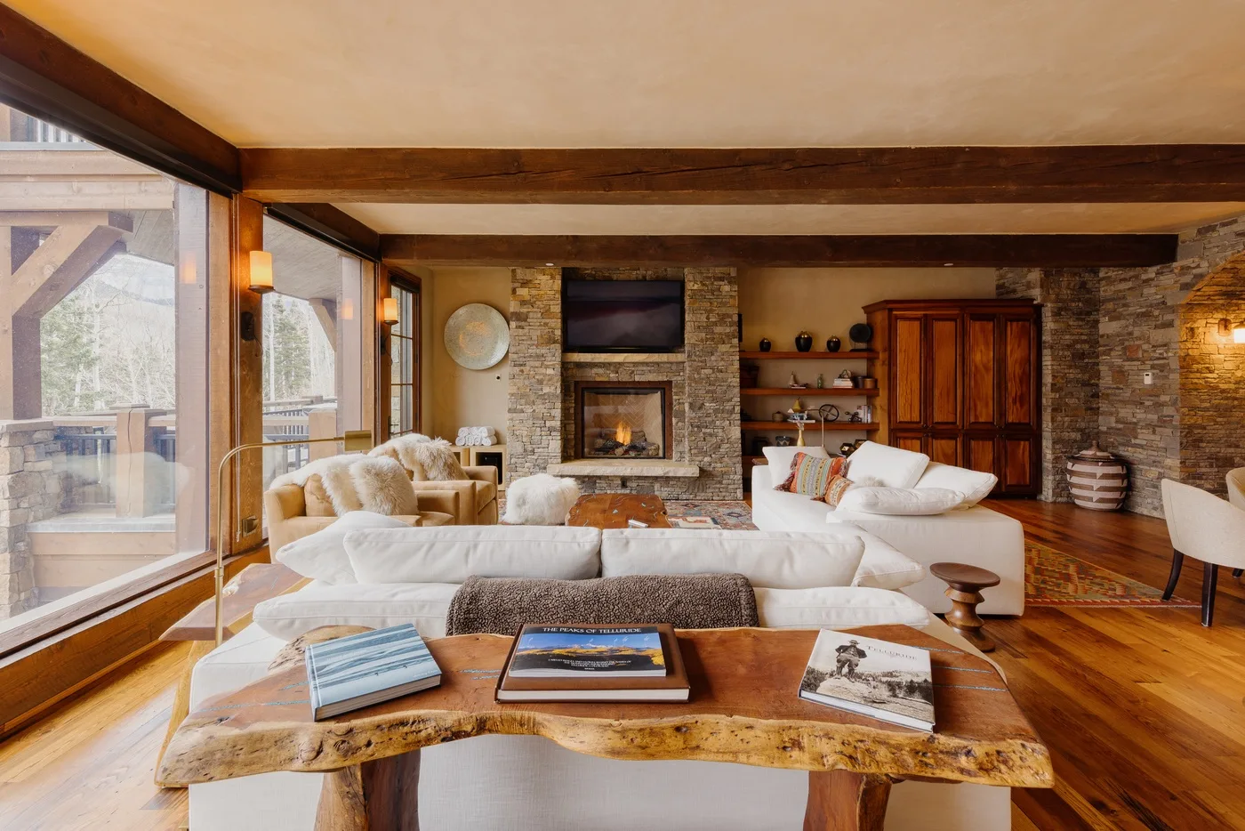 A spacious living room with sofas, a stone fireplace, and large windows.