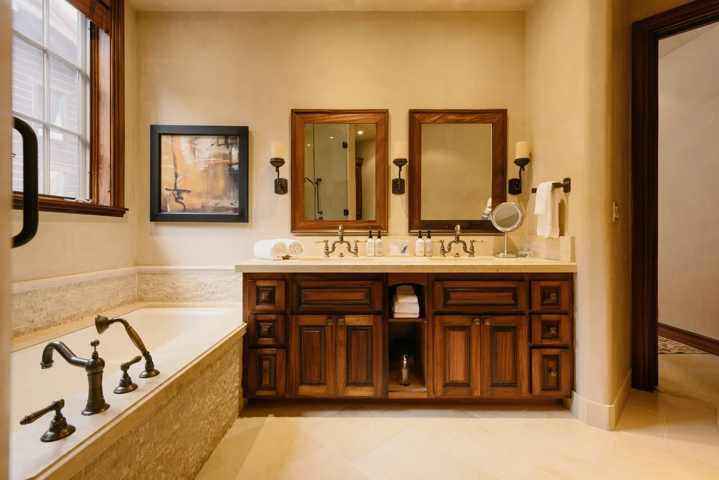 Un baño con tocador de dos lavabos y una bañera junto a una ventana.
