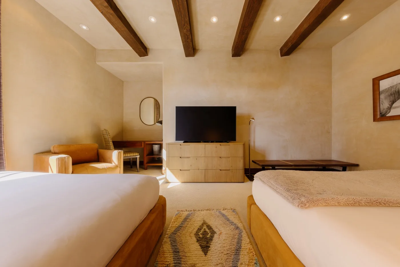 Un dormitorio con dos camas, un televisor y vigas expuestas en el techo.