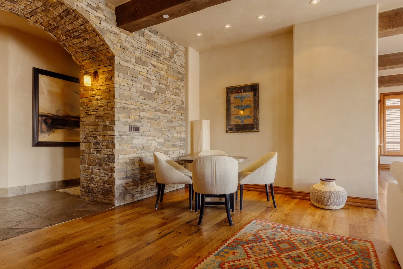 Comedor con una mesa redonda y sillas junto a un arco de piedra.