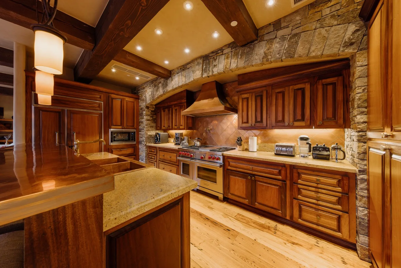 Una cocina amplia con gabinetes de madera oscura, paredes de piedra e isla central.