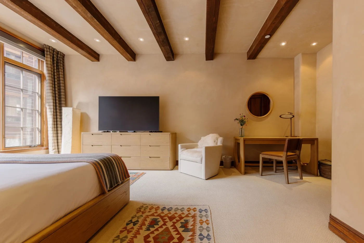 Un dormitorio con cama, televisor y una pequeña zona de estar.
