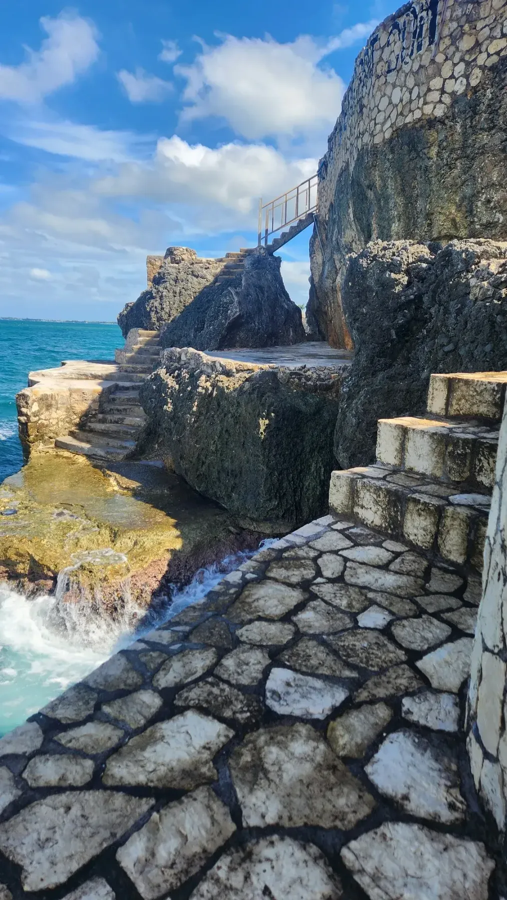 Escalones de piedra que descienden por el acantilado hasta el mar