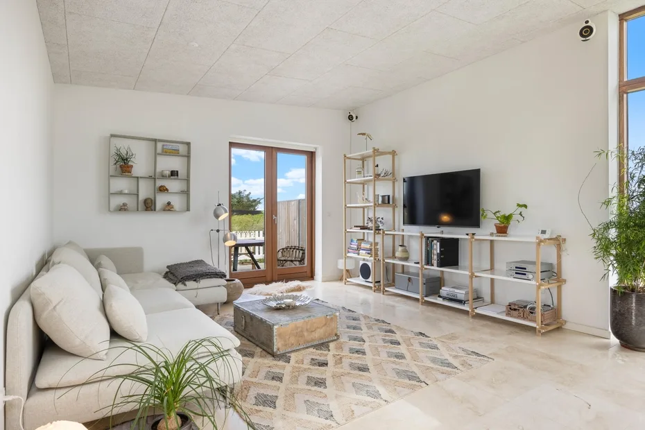A bright living room with seating, a television, and large windows.