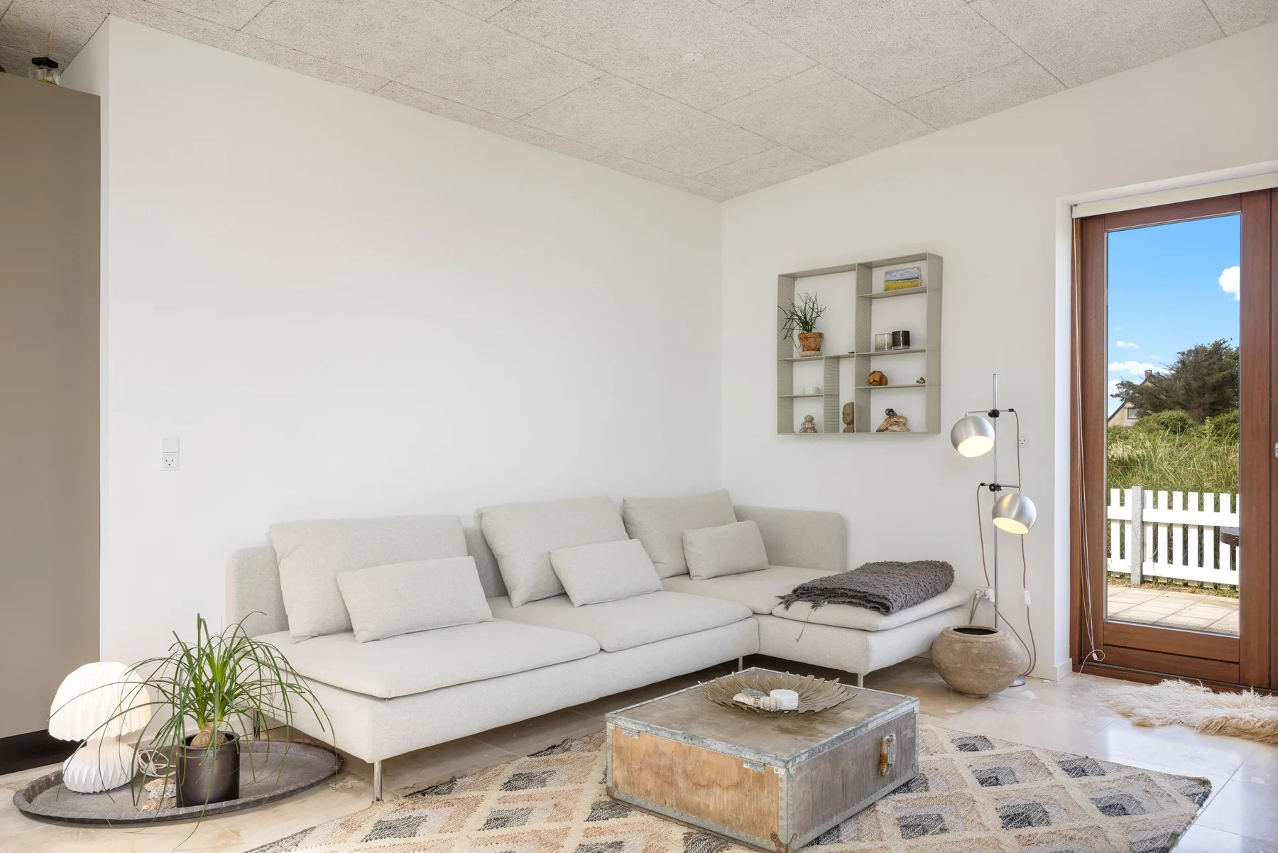 A bright living room with seating and a glass door opening onto a balcony.