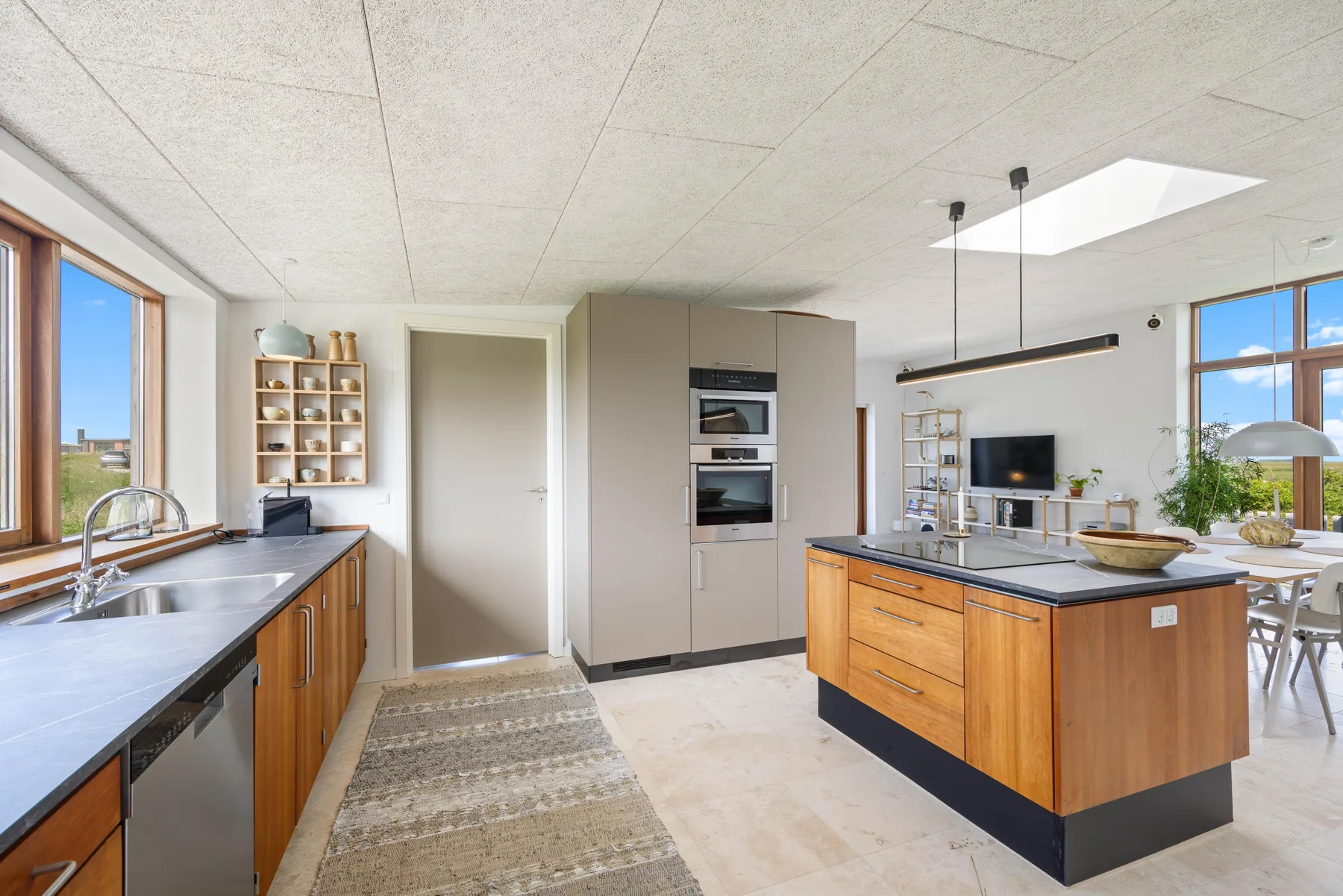 A bright modern kitchen with wood cabinetry and a central island.