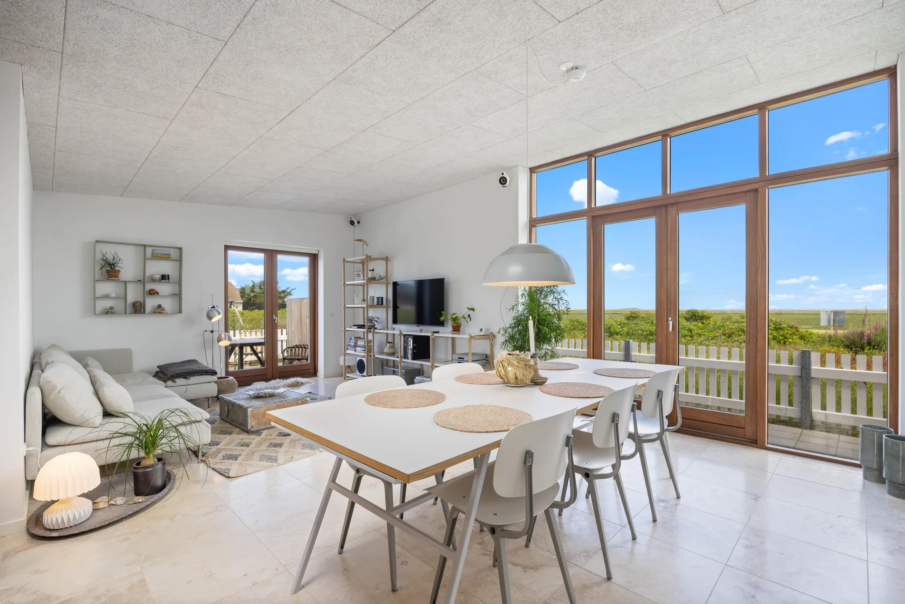 A bright living and dining area with seating beside large windows.
