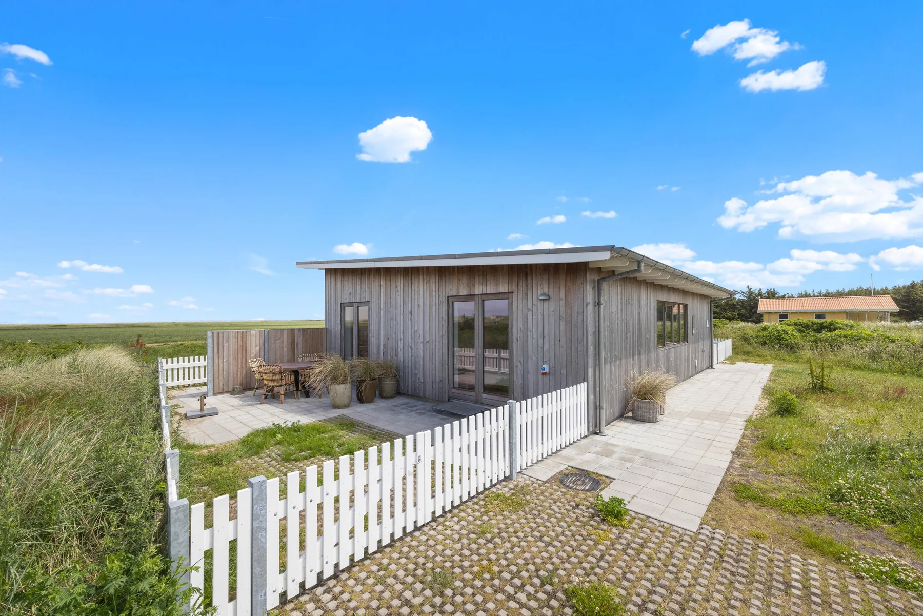 A small cottage with a paved patio and white picket fencing.