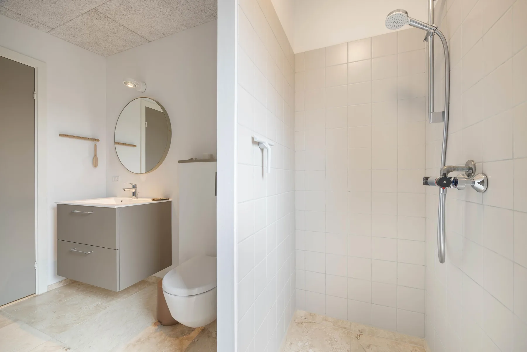 A bright bathroom with a vanity, mirror, toilet, and tiled shower.