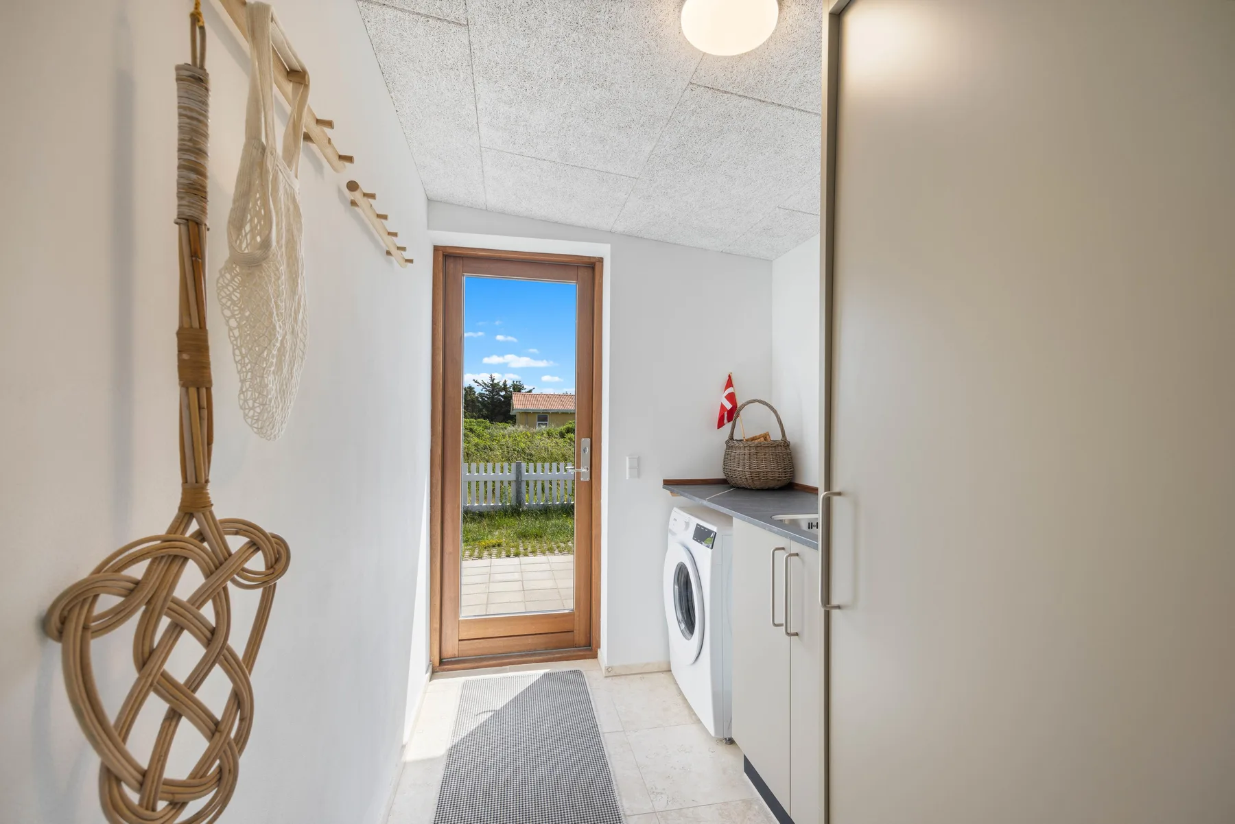 A bright laundry room with a washing machine beside a glass patio door.