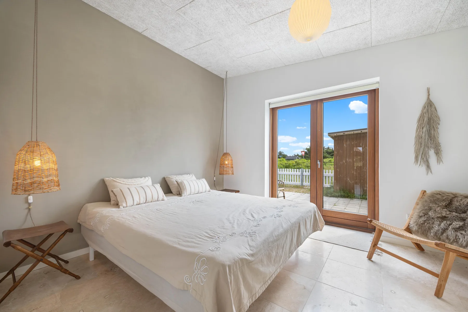 A bright bedroom with a bed and glass doors opening onto a small patio.