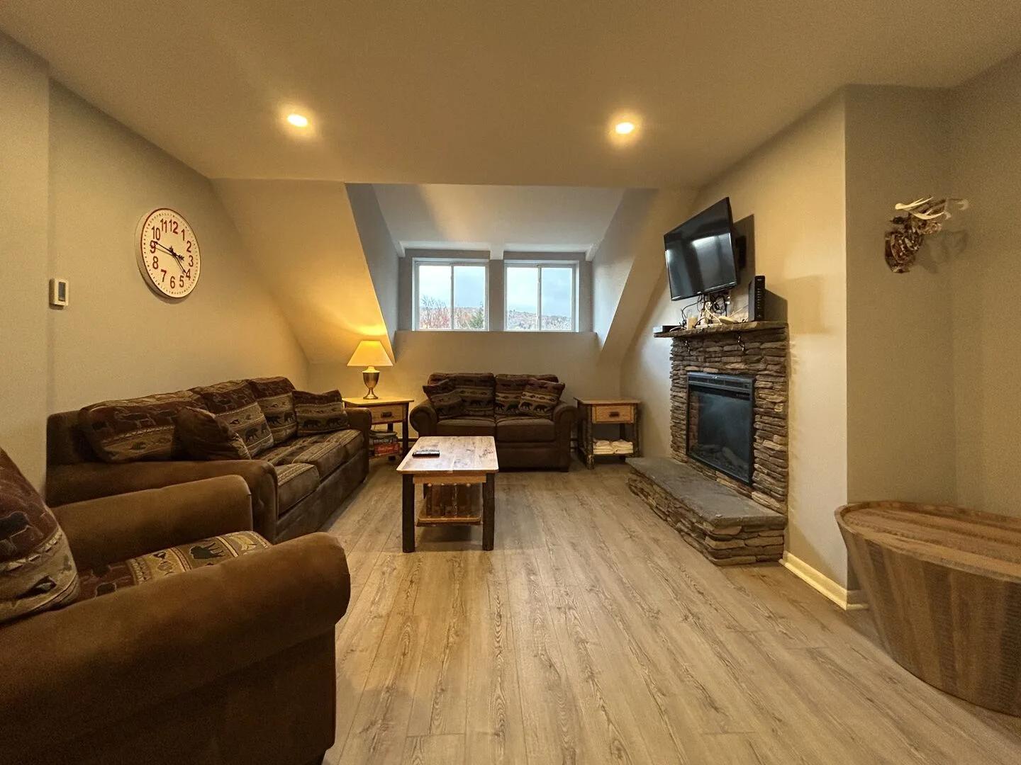 A living room with brown seating, a coffee table, and a stone fireplace.