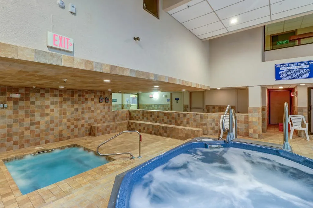 Una zona de piscina cubierta con una bañera de hidromasaje y una piscina más pequeña.